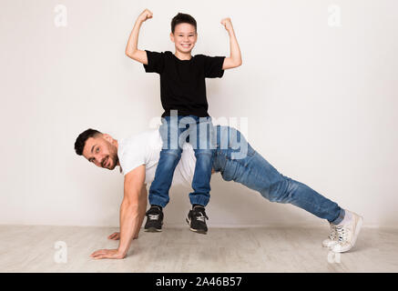 Forte papà facendo spingere ups con figlio sul retro Foto Stock