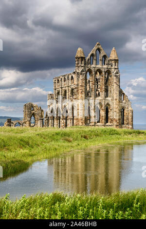 Rovine gotico del XIII secolo Whitby Abbey sul Mare del Nord si riflette nel laghetto Abbazia di Whitby North York Moors National Park in Inghilterra Foto Stock