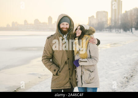 Tema amore e data la natura. Un giovane eterosessuale caucasico giovane ragazzo e ragazza camminare in inverno lungo un lago ghiacciato in inverno. Uomo Barbuto Foto Stock