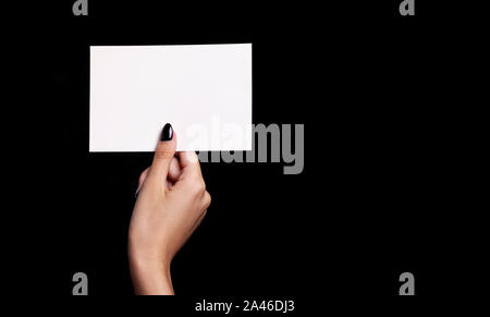Mano azienda carta bianca su sfondo nero - copyspace Foto Stock