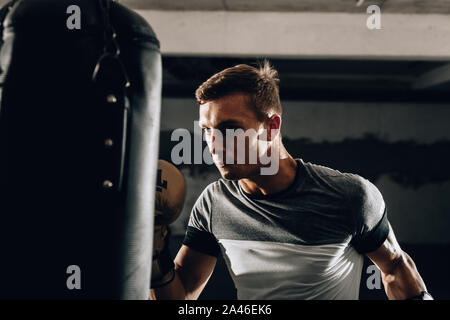 Giovane pugile muscolare utilizzando un sacco da boxe in palestra. Boxer di colpire la punzonatura Speed bag Foto Stock