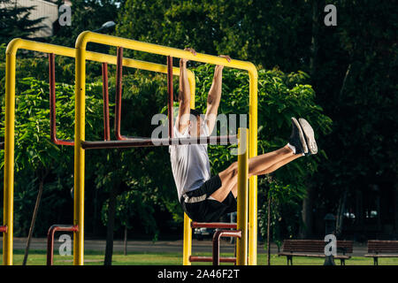 Forte corridore in bianco t-shirt allenamento duro al pomeriggio soleggiato al di fuori, sportivo che lavora fuori crossfit Foto Stock