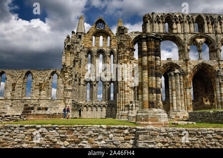 I turisti in piedi all'incrocio del transetto nord in rovine gotiche di Whitby Abbey chiesa cruciforme North Yorkshire, Inghilterra Foto Stock