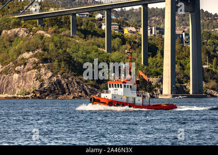 Piccolo rimorchiatore Lars passando sotto Askoy (Askøy) sospensione ponte, al di fuori del porto di Bergen, Norvegia Foto Stock
