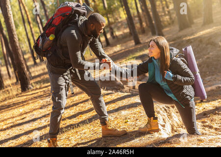 Attraente escursionista aiutare la sua ragazza in salita in campagna Foto Stock