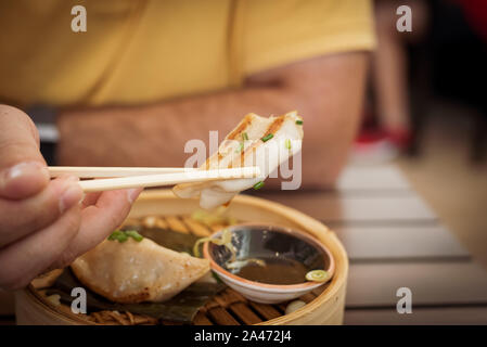 Cibo tailandese. misti, di pollo e gamberetti gyozas vegetale in un Thai vaporizzatore con salsa di soia in una ciotola nero Foto Stock