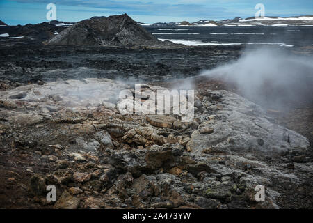 Leirhnjukur vecchio nero e rosso campo di lava con pietre colorate e il fumo proveniente da terra e cielo blu in Islanda, nuvoloso giorno in estate , film effe Foto Stock