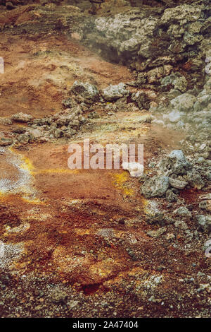 Primo piano di Leirhnjukur nero antico campo di lava con rosso e arancione del suolo e del fumo proveniente dal terreno in Islanda, nuvoloso giorno in estate , film effetto fumetto Foto Stock