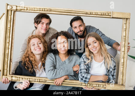 Un gruppo di giovani allegri interculturale amici in informale guardando a voi Foto Stock