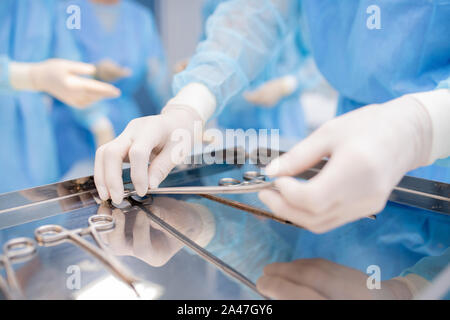 I guanti del chirurgo o assistente prendendo uno degli strumenti sterili Foto Stock