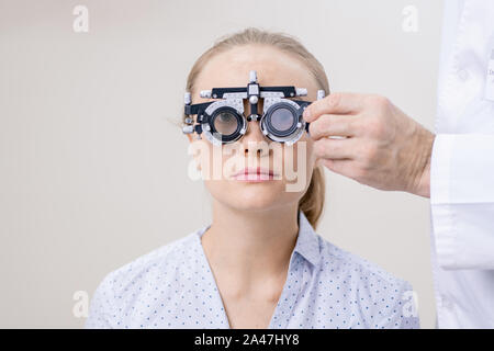 Giovane donna con il suo occhio Visione esaminati durante la ricerca attraverso la lente optometric Foto Stock