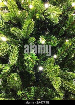 Un frame completo sullo sfondo di un albero di Natale artificiale bianco con le luci fairy in una festosa celebrazione, immagine con spazio di copia Foto Stock