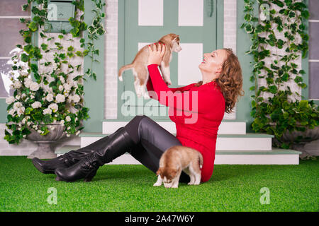 Piuttosto caucasica dimensioni plus woman in red felpa con due simpatici cuccioli di husky su erba verde da solo Foto Stock