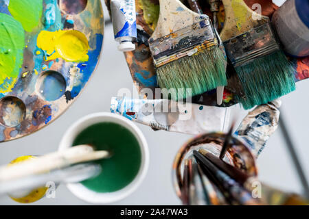 Pennelli sulla tavola e in bicchieri, vernici a olio e la tavolozza dei colori Foto Stock