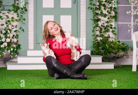 Piuttosto caucasica dimensioni plus woman in red felpa con due simpatici cuccioli di husky su erba verde da solo Foto Stock