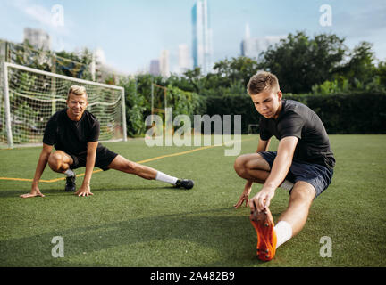 Maschio di giocatori di calcio facendo esercizio di stretching Foto Stock