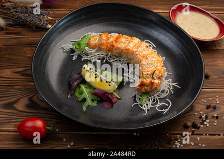 Fette di Salmone cotto nel pane grattugiato con la salsa calda su un cuscino daikon Foto Stock