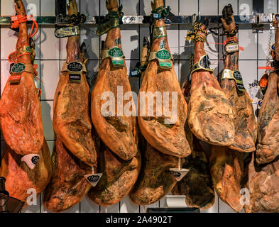 Più intere con osso gambe di spagnolo serrano prosciutto iberico sul display a un mercato locale a Madrid, Spagna Foto Stock