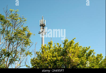 5G antenna al di fuori della citta'. Antenna GSM nella natura. Nuovo 5G technology per il concetto di internet. Nuovo trasmettitore tower e alberi. Foto Stock