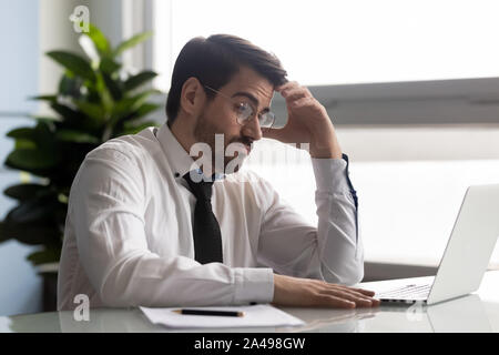 Pensieroso manager guardando sullo schermo del computer, rendendo difficile la decisione. Foto Stock