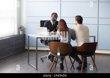 Sorridenti americano africano realtor maschio consulting giovane coppia sposata. Foto Stock
