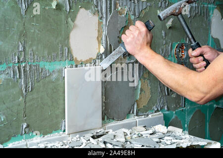 Preparazione di riparare il bagno. L'uomo la rimozione di vecchie piastrelle. Foto Stock