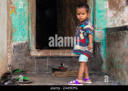 RAGHURAJPUR, INDIA, 14 gennaio 2019 : un ragazzino è in piedi accanto alla sua casa porta anteriore Raghurajpur, l'artigianato famoso villaggio Foto Stock