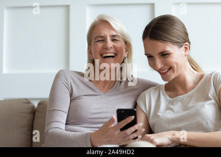 Madre e figlia adulta guardare divertenti video sullo smartphone ridere Foto Stock