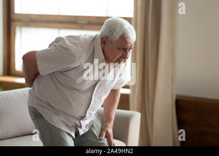 Senior l'uomo si alzò dal lettino sentivo dolori di schiena Foto Stock