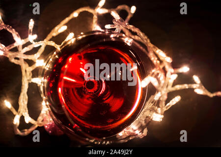 Bicchiere di vino rosso con una ghirlanda di luce Foto Stock