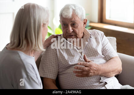 Infermiera geriatrica ascolta uomo anziano che mostra cura e supporto Foto Stock