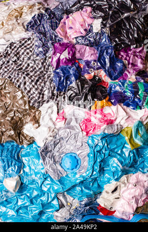 Multicolore, colorate e luminose le cose sono confezionati in un sacco a vuoto. Sfondo. Concetto di risparmio di spazio. Foto Stock