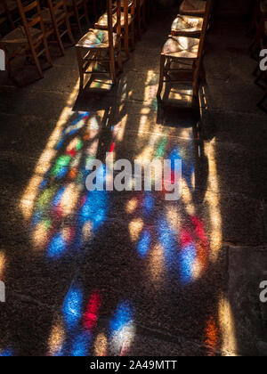 Faith contemplazione Chiesa tinta vetro finestra colorato tardo pomeriggio tramonto luce finestra modello proiettato su sedie chiesa pedine e. bandiera pavimento in pietra in pacifica fede contemplativa ambiente religioso Foto Stock