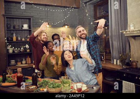 Multi-etnico gruppo di giovani prendendo selfie foto tramite smartphone mentre godendo di partito e la cena insieme Foto Stock