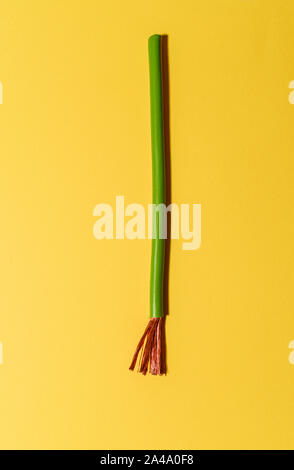 Cavo elettrico su sfondo giallo. Si diffondono i fili di rame. Minimalista sfondo elettrico. Foto Stock