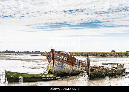Il Noirmoutier barche cimitero. Un gruppo di relitti di antiche in legno barche da pesca vengono impilati sul fango. Foto Stock