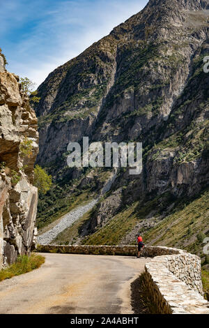 Femmina matura ciclista in sella alla strada tranquilla fino ti Saint Christophe Oisans, Alpi occidentali,Francia. Foto Stock