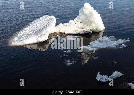 Drifting di grandi blocchi di ghiaccio sul fiume, contro lo sfondo dell' acqua scura, su una molla giornata di sole. Foto Stock