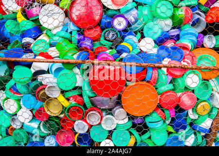 Grande collezione di plastica colorata bottiglia tops formando una scultura cablata. Foto Stock