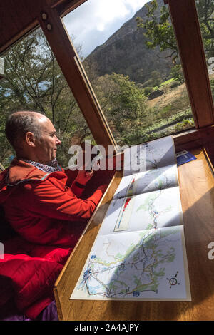 Fotografare passeggeri utilizzando un telefono cellulare all'interno di una rampa coach sul Ffestiniog & Welsh Highland Railway con una mappa del percorso del treno sul tavolo Foto Stock