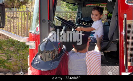 I genitori prendere le foto dei loro bambini come arrivare a esplorare il camion dei pompieri presso la stazione dei vigili del fuoco open house Foto Stock