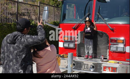 I genitori prendere le foto dei loro bambini come arrivare a esplorare il camion dei pompieri presso la stazione dei vigili del fuoco open house Foto Stock