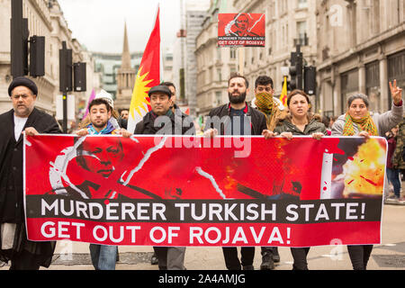 Londra, Regno Unito. 13 ottobre 2019. I manifestanti pro-curdi marciano attraverso il centro di Londra portando con sé una grande bandiera rossa che condanna le azioni militari dello Stato turco a Rojava, nel nord della Siria. Lo striscione presenta slogan e immagini audaci, con cartelli aggiuntivi tenuti dai manifestanti. La protesta evidenzia la solidarietà curda, il sentimento anti-guerra e l'opposizione all'intervento straniero in Siria. Penelope Barritt/Alamy Live News Foto Stock