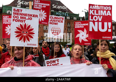 COPENHAGEN, Danimarca - 11 ottobre 2019: migliaia di persone si riuniscono a un popolo il clima di marzo a Copenhagen City Hall Square e ha chiesto la rapida e ampia azione per il clima, che segna la conclusione del C40 World Summit sindaci durante questa settimana a Copenaghen. A destra un cartello con il testo in inglese: "ambizioso clima legge ora'. Questo si riferisce ad una grande richiesta per un quadro normativo condizione per i governi danese clima sforzi, che comprende obblighi per definire il legame degli obiettivi climatici. Foto Stock