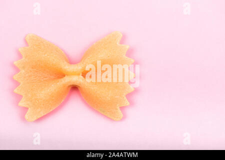 Farfalle bow tie pasta sagomata macro su sfondo rosa isolato con tracciato di ritaglio Foto Stock