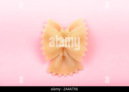 Farfalle bow tie pasta sagomata macro su sfondo rosa Foto Stock