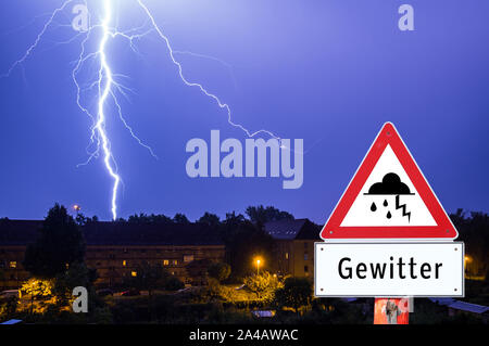 I temporali di sera con le luci della città tedesca di segno di avvertimento Foto Stock