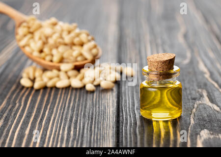 Essenziale olio di cedro in piccola bottiglia di vetro con il mucchio di dadi sul tavolo di legno Foto Stock