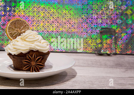 Holiday cupcake con glassa di mascarpone, essiccate di agrumi, arancio, limone e decorazione di calce, cookie cutters e anice stelle. Luminoso dello sfondo colorato. Foto Stock