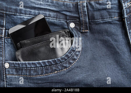 In pelle nera a portafoglio maschio e smart phone in tasca dei jeans con copia spazio per il testo Foto Stock